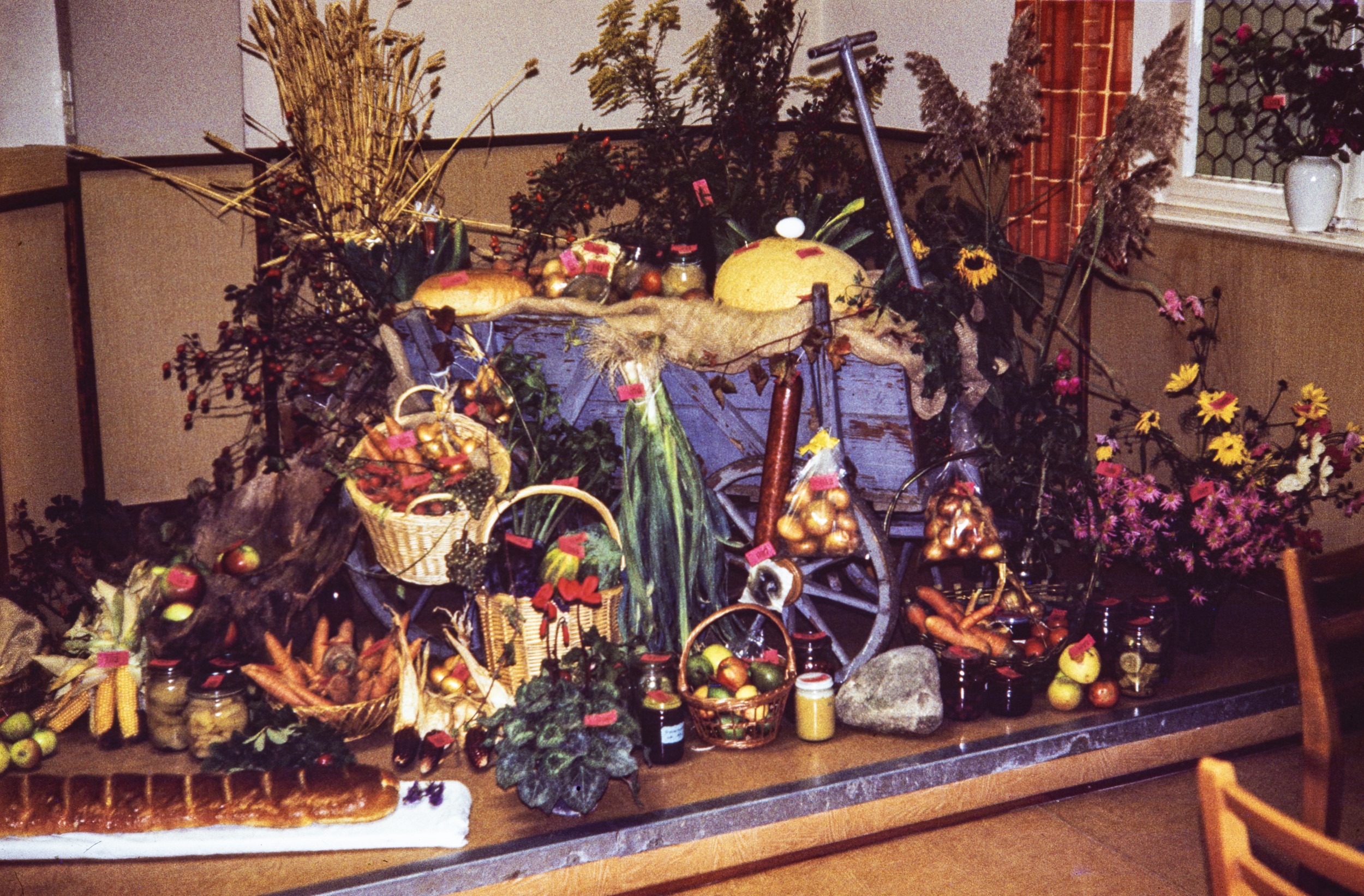 OBst und Gemüse, frisch und verabreitet rund um einen alten Leiterwagen angeordnet. Erntedank 1983